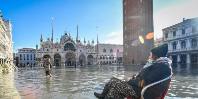 Eine Frau sitzt auf einem Stuhl im Hochwasser auf dem Markusplatz – inzwischen ist das Wasser wieder weg. Venedig