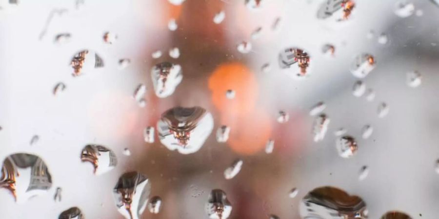 Eine Weihnachtspyramide spiegelt sich in Regentropfen auf einer Glasscheibe. Foto: Julian Stratenschulte/dpa