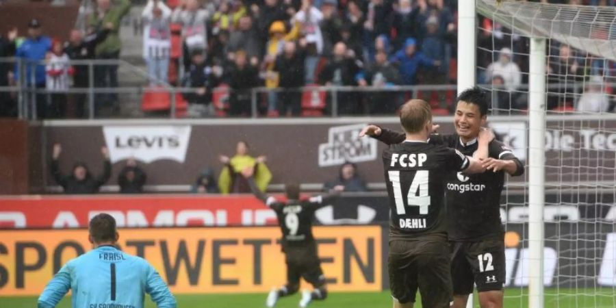 Ryo Miyaichi (r) und Mats Möller Daehli (2.v.r) vom FC St. Pauli jubeln nach dem Tor zum 2:0 neben Sandhausens Torwart Martin Fraisl. Foto: Daniel Bockwoldt