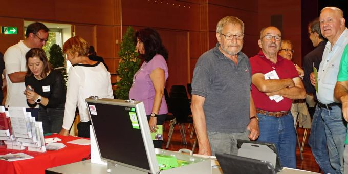 Besuchende informieren sich am Tischmarkt über die verschiedenen Angebote. Besuchende informieren sich am Tischmarkt.
