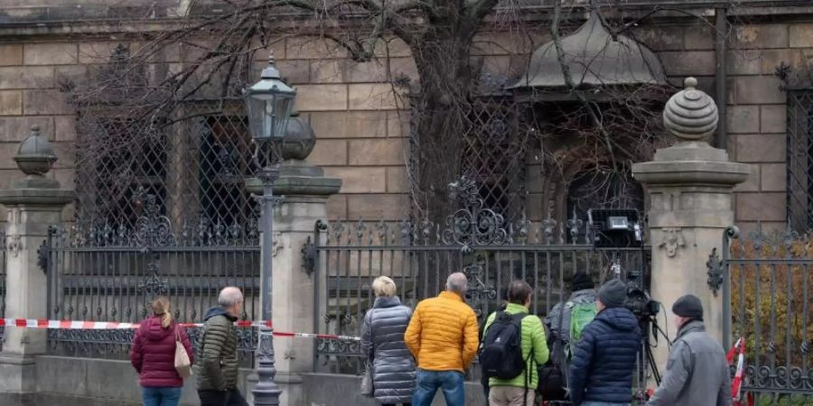 Passanten stehen vor den Gitterfenstern des Grünen Gewölbes am Residenzschloss hinter einem Zaun. Foto: Sebastian Kahnert/dpa-Zentralbild/dpa