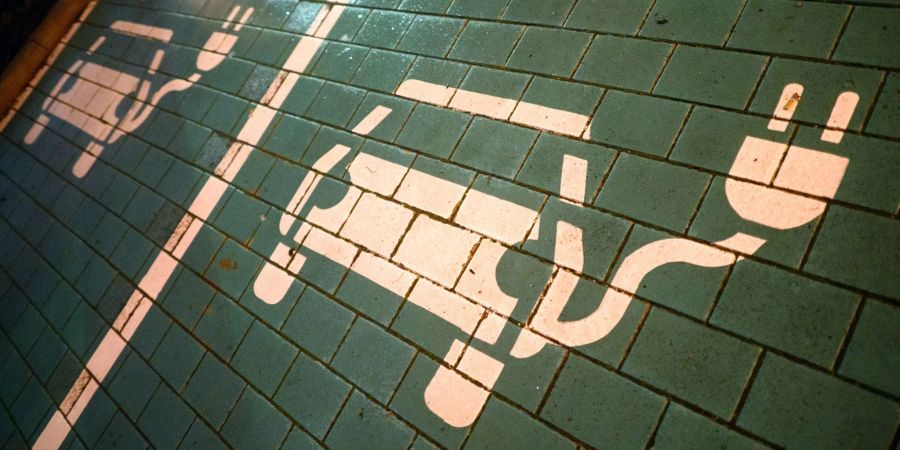Symbole markieren Parkplätze mit einer öffentlichen Ladesäule für Elektroautos an einem Einkaufszentrum.