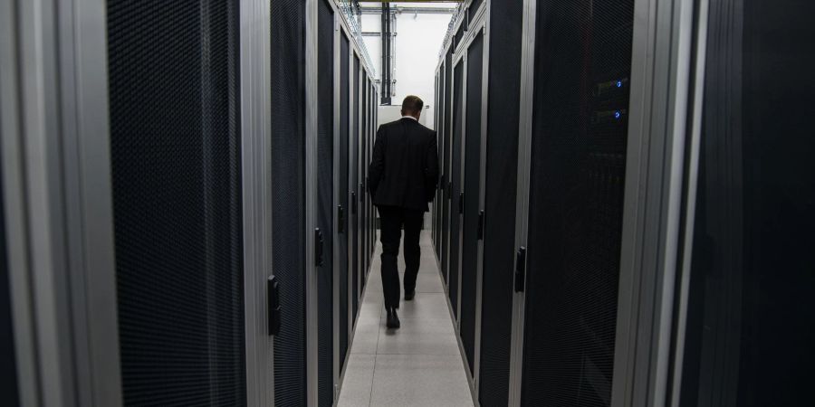 Ein Mitarbeiter der Firma DE-CIX geht zwischen Server-Schränken hindurch.