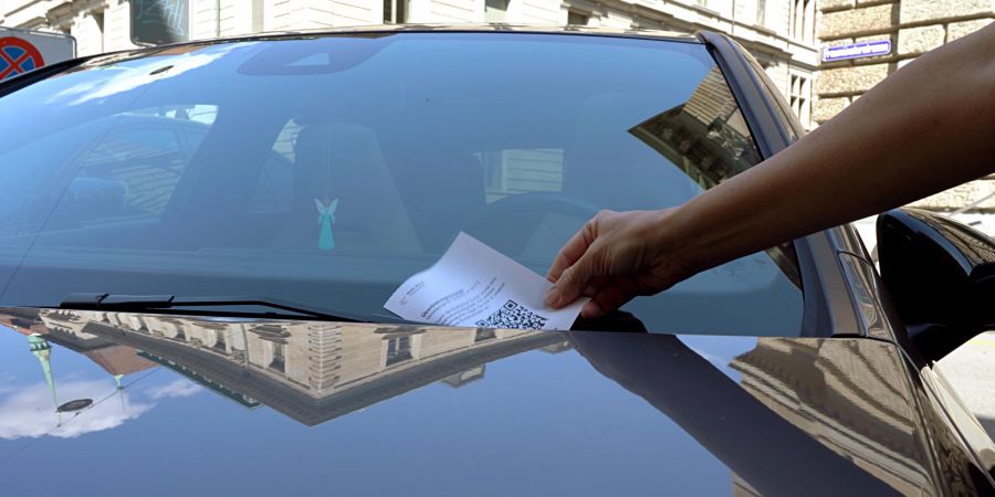 Ein Strafzettel wegen Falschparkens wird auf einer Auto-Windschutzscheibe hinterlegt. (Symbolbild)