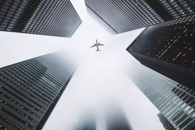 Wer doch mal in den Flieger steigen muss, der kann die ausgestossenen CO2-Emissionen kompensieren. Flugzeug über den Gebäuden.