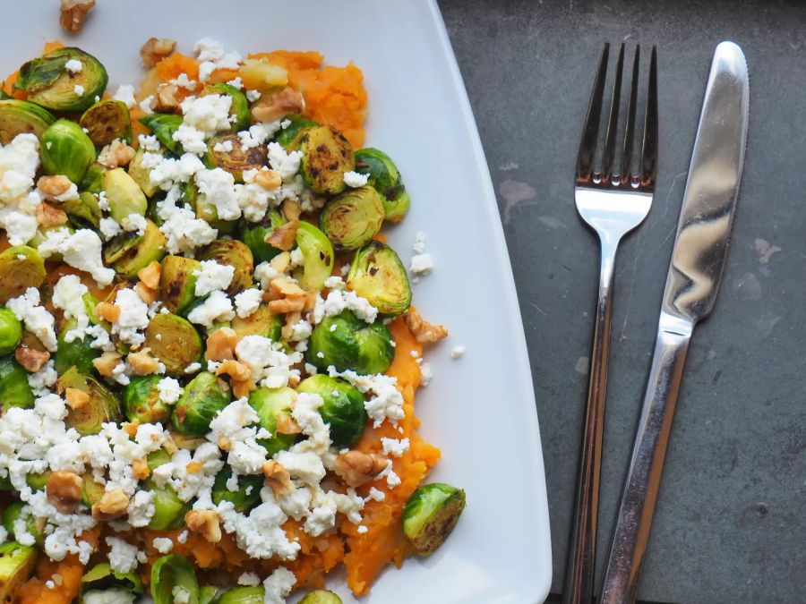 Essen mit Rosenkohl auf Teller mit Besteck