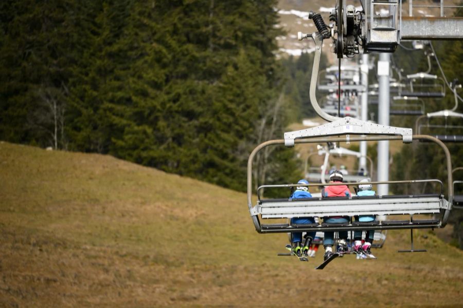 Skifahrer auf einem Sessellift in Villars-sur-Ollon VD. Darunter ist es grün statt weiss.