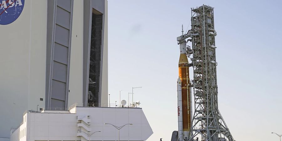 Die Rakete «Space Launch System» mit der «Orion»-Kapsel wird auf einer Art Transportwagen aus der Werkshalle herausgefahren auf dem Weg zur Startrampe 39B im Kennedy Space Center. Foto: John Raoux/AP/dpa