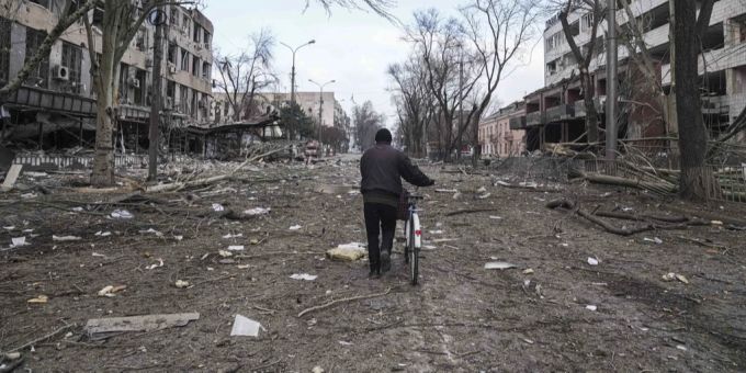 Ein Mann schiebt sein Fahrrad nach einem Bombenangriff durch die Trümmer in Mariupol. In der Stadt wird der Ukraine-Krieg besonders brutal geführt. Ukraine Krieg