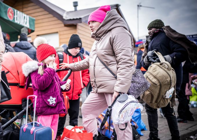 Die Ukrainerin Krystyna Krajnik wartet mit ihren Kindern Alla und Swjatoslaw nach ihrem Grenzübertritt von Schehyni in der Ukraine nach Medyka in Polen von Polizeibeamten am Rand des Grenzgebiets auf ihren Weitertransport. Foto: Michael Kappeler Ukraine Konflikt
