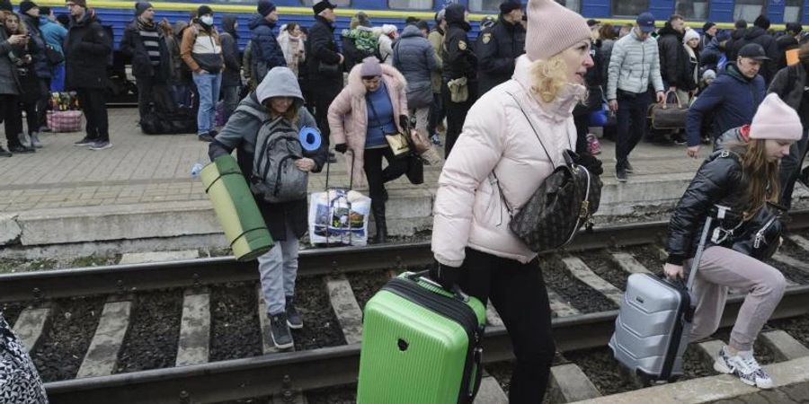 Menschen versammeln sich am Bahnhof in Lwiw im Westen der Ukraine, um einen Zug zu nehmen und die Ukraine in die Nachbarländer zu verlassen. Russische Truppen haben den erwarteten Angriff auf die Ukraine gestartet und drangen in die Hauptstadt vor. Foto: Mykola Tys/AP/dpa