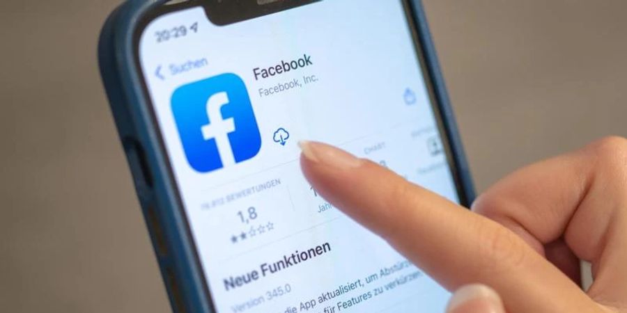 Eine Frau bedient die Facebook-App auf ihrem Handy. Foto: Mohssen Assanimoghaddam/dpa