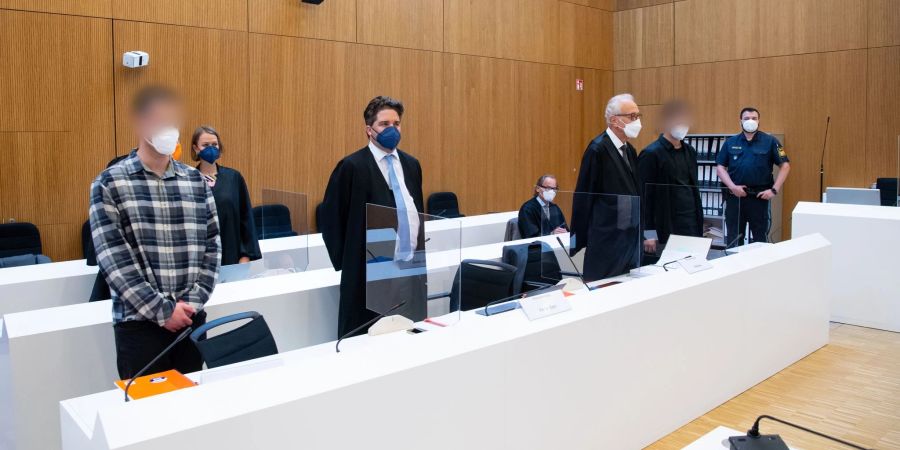 Die zwei wegen Mordes angeklagten Männer (l und 2.v.r.) mit ihren Anwälten vor Beginn der Verhandlung im Sitzungssaal.