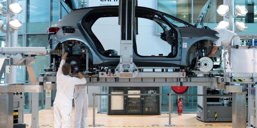 VW-Mitarbeiter montieren im Rahmen eines Presserundgangs in der Gläsernen Manufaktur von Volkswagen in Dresden bei der sogenannten Hochzeit die Karosserie und den Antriebsstrang eines VW ID.3. Foto: Sebastian Kahnert/dpa-Zentralbild/dpa