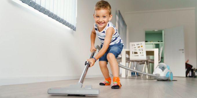 Jüngere Kinder packen oft gerne im Haushalt mit an. Diese Motivation gilt es zu unterstützen. Junge, Staubsauger, Haushalt