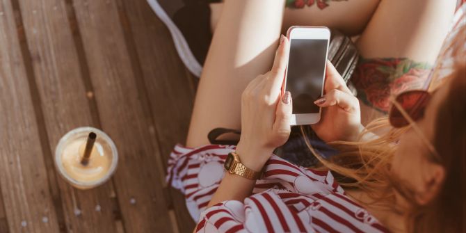 junge frau schaut auf smartphone, holzsteg, sommer