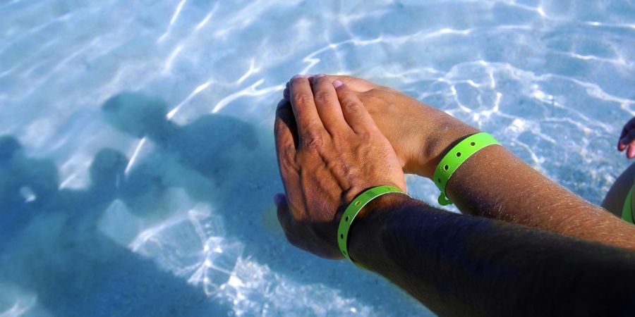 Paar im Pool mit All-Inclusive Armbändern.