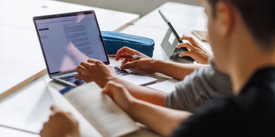 Schüler eines Gymnasiums sitzen vor einem Computer und benutzen ein KI-Tool.