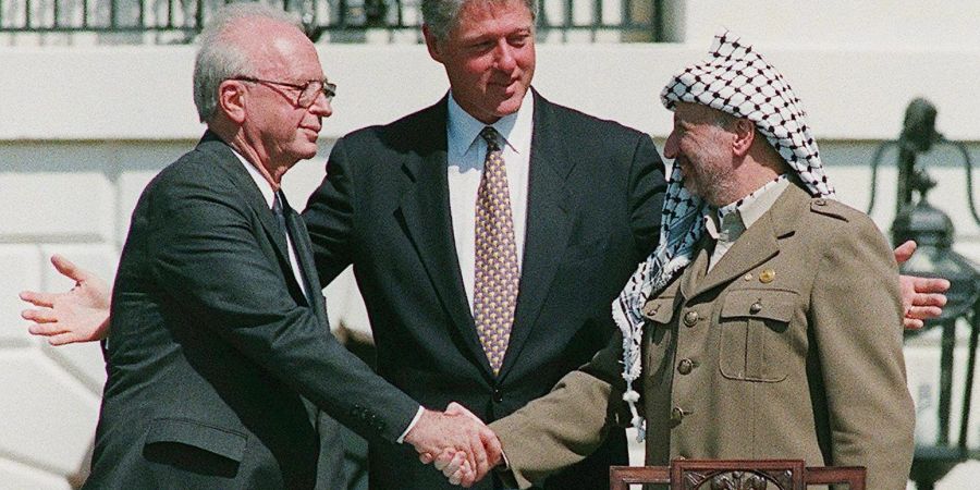 Ein Handschlag, der die Hoffnungen auf einen Frieden zwischen Israel und den Palästinensern symbolisiert: Der damalige Ministerpräsident von Israel, Izchak Rabin (l), und Jassir Arafat (r), damaliger Vorsitzender der Palästinensischen Befreiungsorganisation PLO, geben sich im Beisein von Ex-US-Präsident Bill Clinton die Hand.