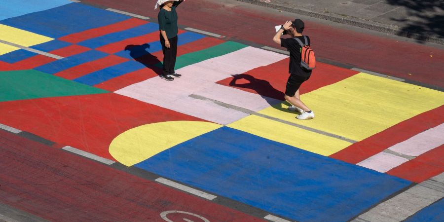 Touristen nutzen die bunt bemalte Fahrbahn am Mainkai für ein Erinnerungsfoto.