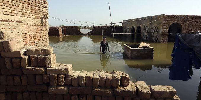 Eine Person geht durch das Hochwasser nach starken Regenfällen. Foto: Fareed Khan/AP/dpa pakistan