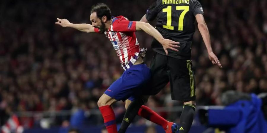 Atleticos Juanfran Torres (l) und Juve-Stürmer Mario Mandzukic kämpfen um den Ball. Foto: Manu Fernandez/AP