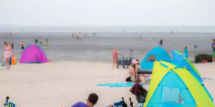 Touristen entspannen am Badestrand von Schillig in Niedersachsen. Foto: Mohssen Assanimoghaddam/dpa