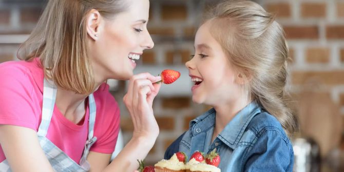 Frau mit Kind isst Erdbeeren