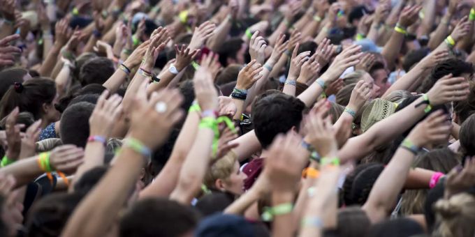 Menschen halten ihre Hände an einem Openair-Konzert in die Höhe. openair