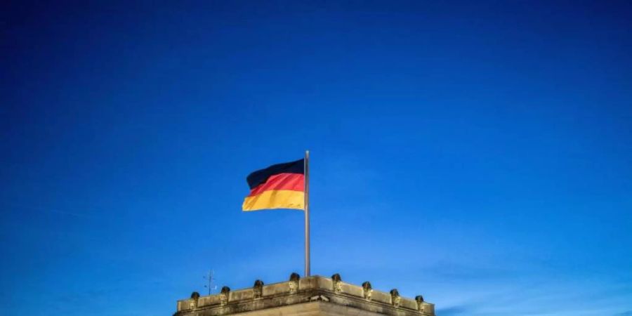 Die Deutschlandfahne weht vor dem Abendhimmel auf dem Reichstagsgebäude im Wind. Foto: Kay Nietfeld/dpa