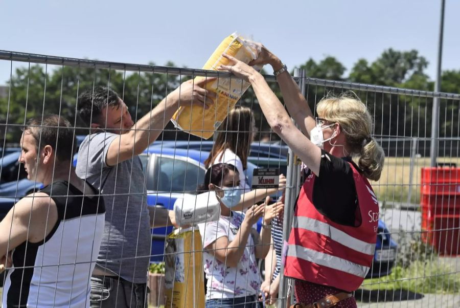 Eine Helferin übergibt Windeln an die Tönnies-Angestellten. Wegen des Corona-Ausbruchs sind sie hinter Zäunen und in ihren Wohnungen in Quarantäne.