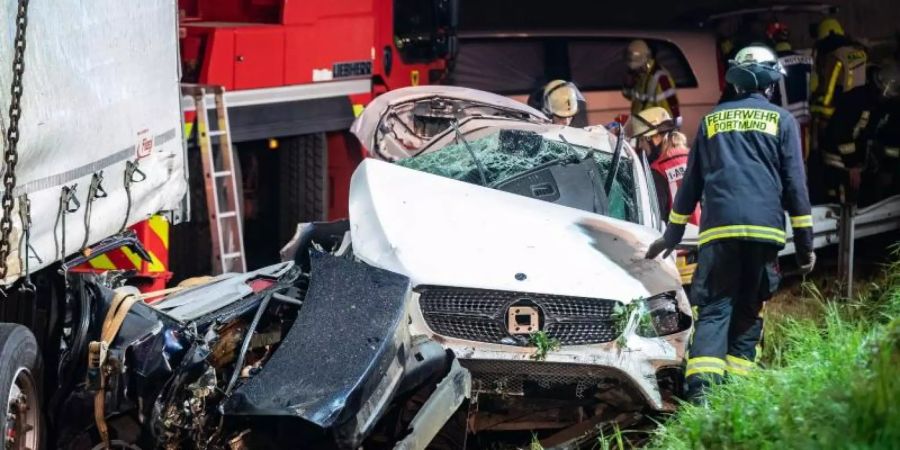 Einsatzkräfte der Feuerwehr stehen auf der A2 neben völlig zerstörten Fahrzeugen. Foto: Marcel Kusch/dpa