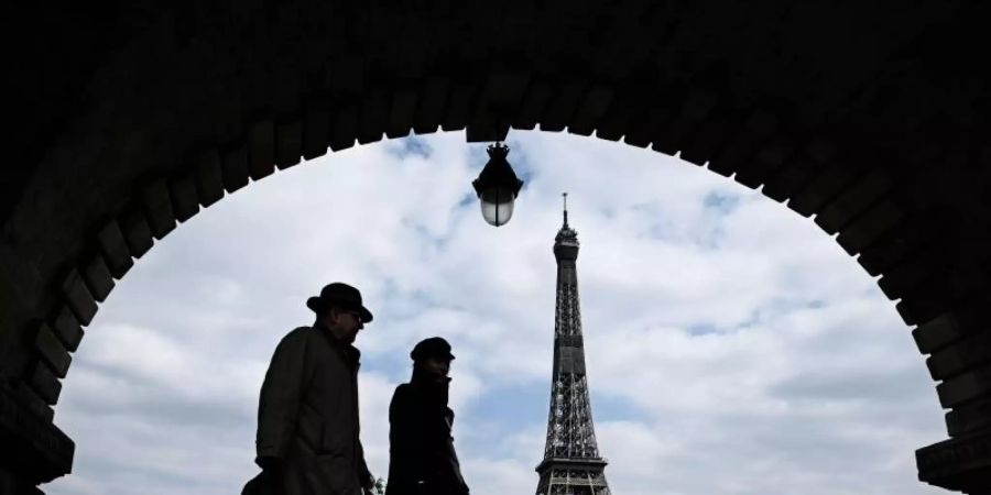 Passanten gehen auf der Brücke «Pont de Bir-Hakeim», mit Blick auf den Eiffelturm. Foto: Philippe Lopez/AFP/dpa