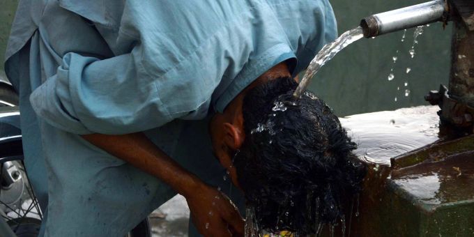 Ein junger Mann in Pakistan erfrischt seinen Kopf unter einem Wasserhahn. pakistan hitze