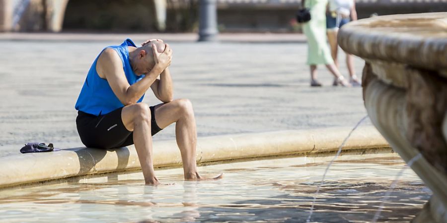 Ein Mann kühlt sich im zentralen Brunnen auf der Plaza de España in Sevilla ab. Foto: Daniel Gonzalez Acuna/dpa