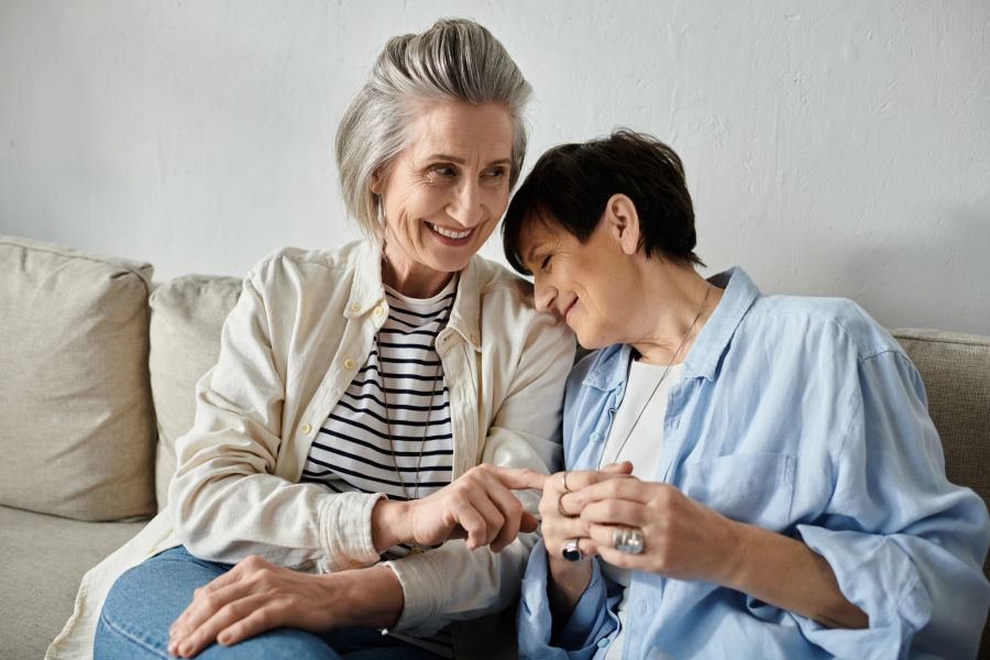 zwei ältere damen, lachen gemeinsam, auf couch sitzend