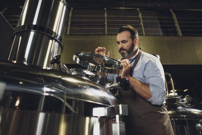 Ein Bierbrauer kontrolliert einen Biertank. Rohstoffe