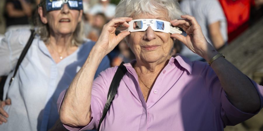 Zwei Frauen beobachten mit Schutzbrillen ausgerüstet am Mittwochabend auf der Zürcher Polyterrasse, wie der Mond die Sonne während der partiellen Sonnenfinsternis verdunkelt.