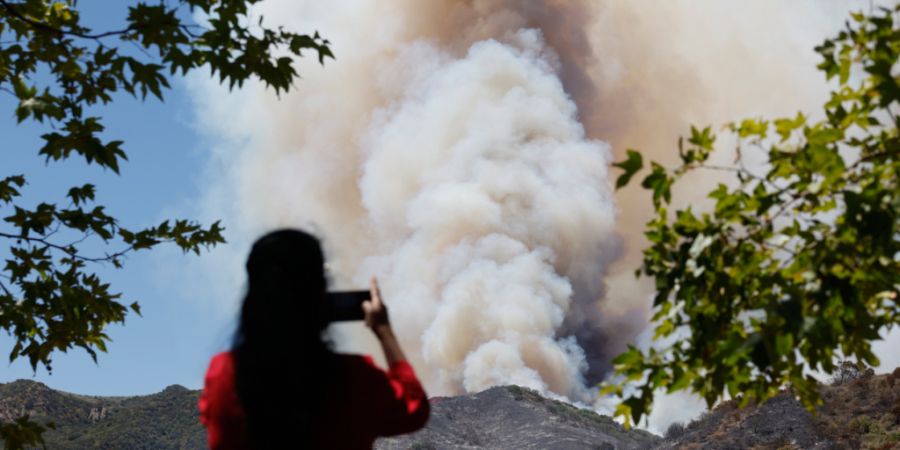 Eine Frau fotografiert den Rauch eines Waldbrandes in Simi Valley. Foto: Caroline Brehman/FR172323 AP/AP/dpa