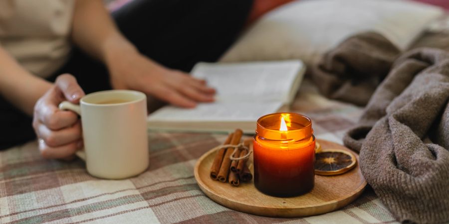 Frau liest Buch bei Kerzenschein