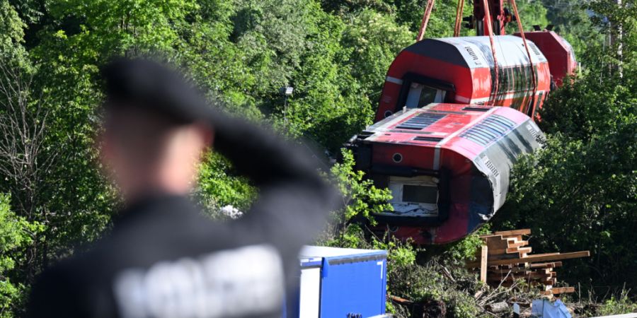 ARCHIV - Ein Polizist betrachtet aus der Ferne den Unfallort, wo zwei Waggons noch geborgen werden müssen. Foto: Angelika Warmuth/dpa