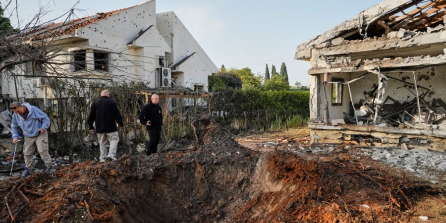 ARCHIV - Menschen inspizieren Häuser, die durch ein aus dem Libanon abgeschossenes Projektil beschädigt wurden. Foto: Baz Ratner/AP/dpa