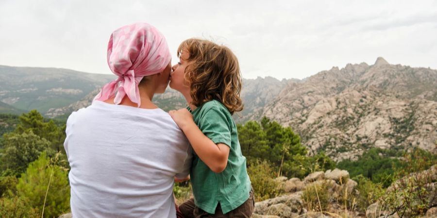 Mutter mit Kopftuch nach Krebserkrankung beim Wandern mit Sohn