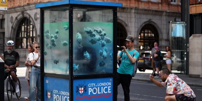 Menschen versammeln sich, um ein Kunstwerk des britischen Strassenkünstlers Banksy auf einem alten Wachhäuschen der Polizei in der City of London, Grossbritannien, 11. August 2024, zu betrachten. Es ist das siebte Tierkunstwerk, das der Künstler in der vergangenen Woche für sich beansprucht hat. Banksy hat sieben Tage lang ein Kunstwerk pro Tag für sich beansprucht und jeden Tag um 13 Uhr Ortszeit ein Foto in den sozialen Medien gepostet. EPA/ANDY REGEN