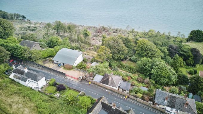 Hinter Palmen und Grün liegt der Blick aufs Wasser. Haus billig Klippe