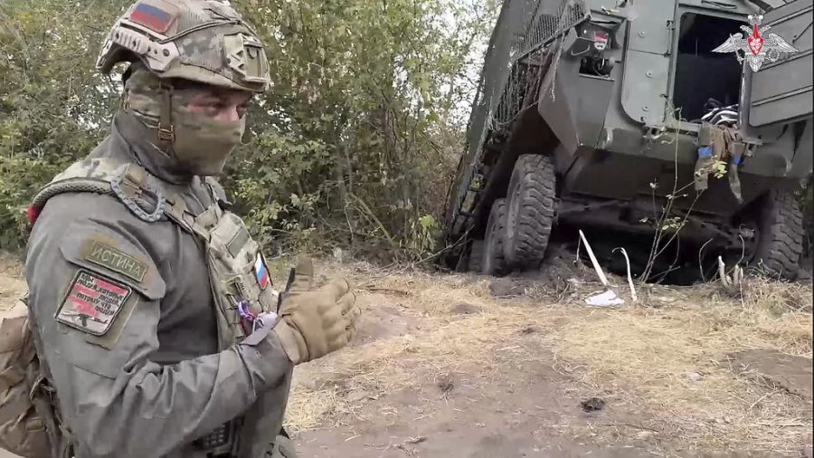 Ein russischer Soldat steht neben einem beschädigten Militärfahrzeug der Ukraine im umkämpften Grenzgebiet Kursk.