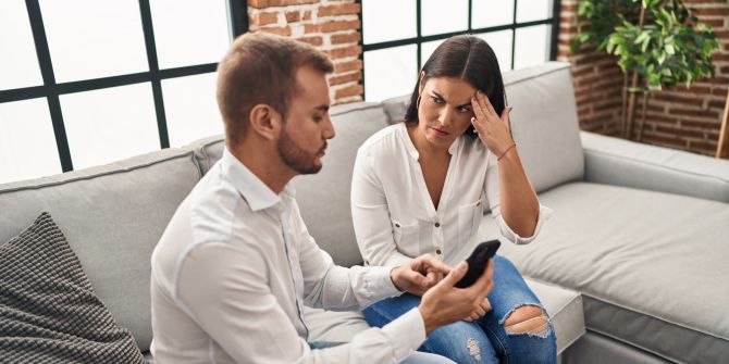 Mann zeigt skeptischer Frau sein Smartphone
