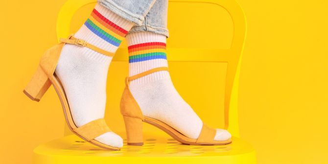 Füsse mit weissen Socken und gelben Sandaletten auf einem gelben Stuhl