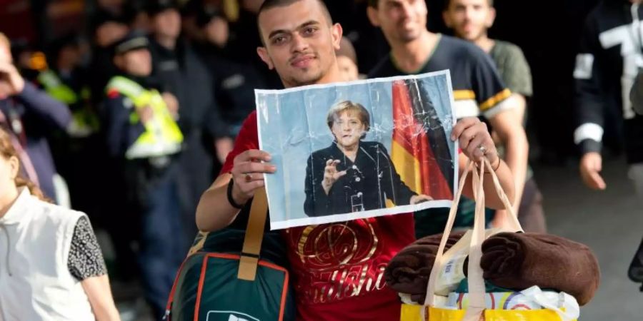 Ein Flüchtling, der kurz zuvor mit einem Zug angekommen ist, hält voller Hoffnung ein Foto von Angela Merkel in den Händen.(Archiv). Foto: Sven Hoppe/dpa