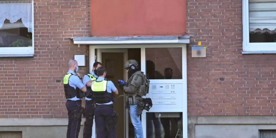 Polizei und ein SEK-Beamte während ihres Einsatzes vor einem Mehrfamilienhauses in Krefeld. Foto: Alexander Forstreuter/-/dpa
